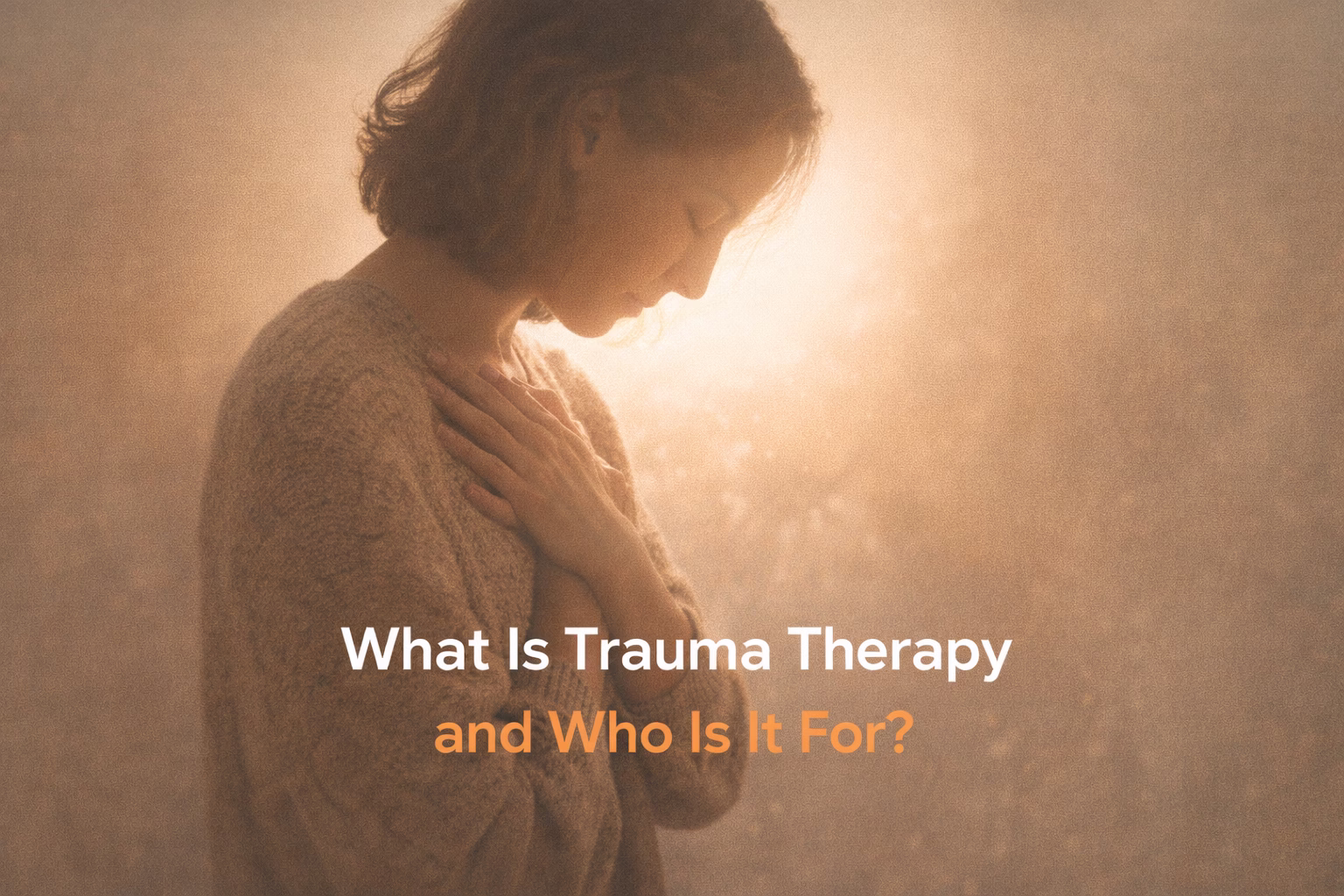 A person holding their chest in soft light, symbolizing emotional healing and support through trauma therapy.